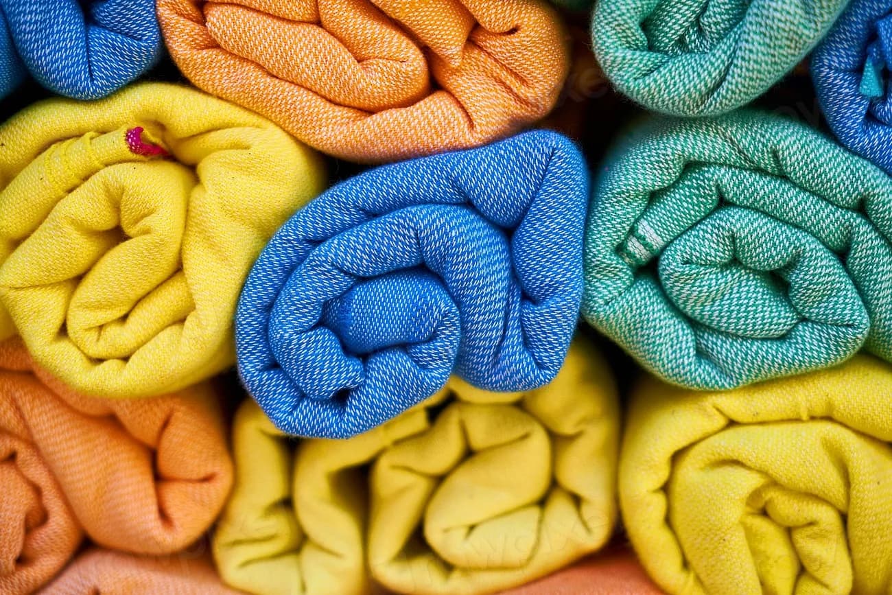 Rolled cotton textiles in yellow, blue, orange, and green