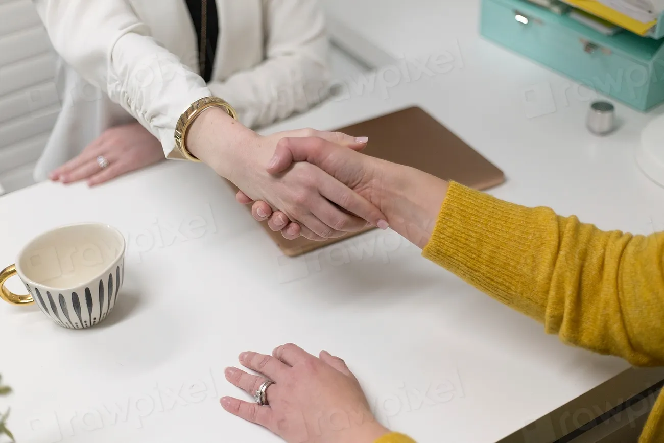 Two professionals shaking hands across a desk