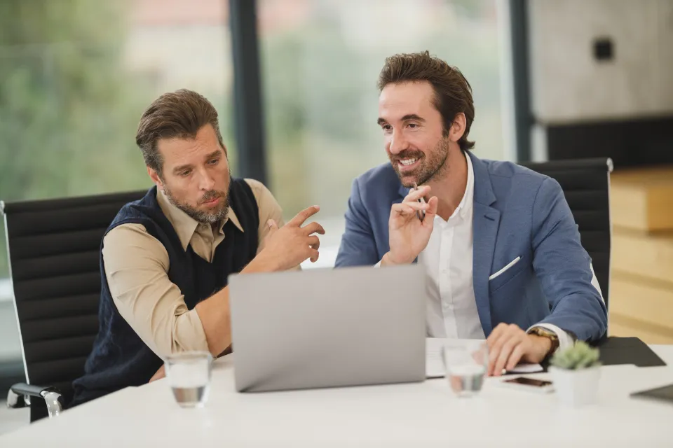 Two consultants discussing strategy at a laptop